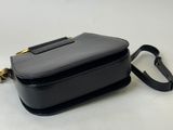 a black purse sitting on top of a table next to a white wall
