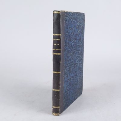 un livre bleu aux bords dorés posé sur une surface blanche