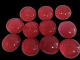 six red gummy balls are arranged in a pyramid on a black surface
