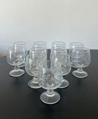 six clear wine glasses are lined up on a black table