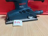 un gros plan d'une ponceuse orbitale Bosch posée sur une table en bois