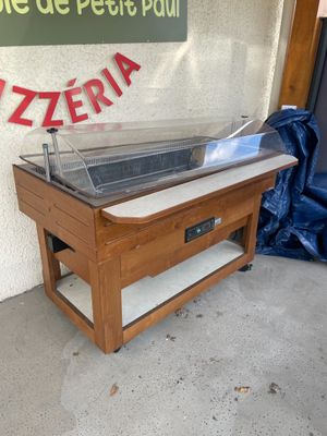 une table en bois sur laquelle est posée une casserole en métal, devant un panneau