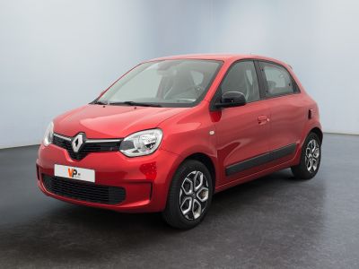 Une voiture rouge est garée dans une pièce au sol noir.