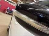 a close up of a car ' s side mirror with a red wall in the background