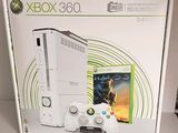 une console Xbox 360 blanche dans son emballage, avec deux manettes posées devant la boîte