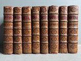 several old books are lined up on a shelf in a row