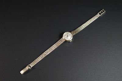 une image représentant une montre-bracelet sertie de diamants, posée sur une surface noire