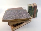 several old books stacked on top of each other on a white surface