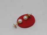 a close up of a pair of pearl earrings on a red surface
