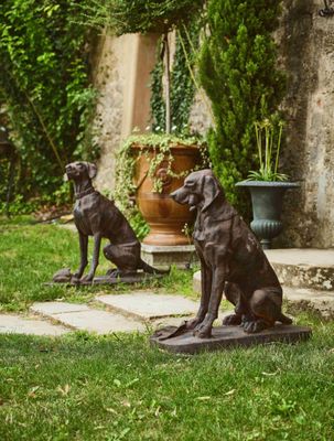 deux statues de chiens assis dans l'herbe, à l'extérieur