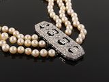 a close up of a necklace with pearls and a clasp