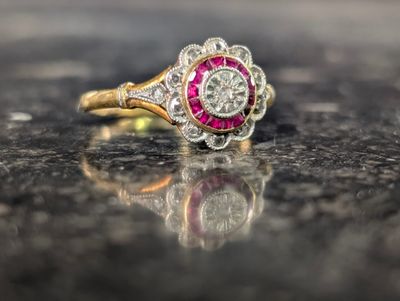 une photo d'une bague sertie de diamants et de rubis posée sur une table