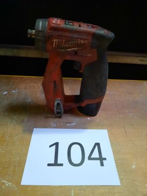 une perceuse sans fil rouge posée sur une table à côté d'un chiffre