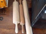 trois rouleaux à pâtisserie posés sur une table en bois, à côté d'un micro-ondes