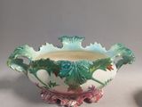 a vase with a green leaf decoration on it next to a bowl