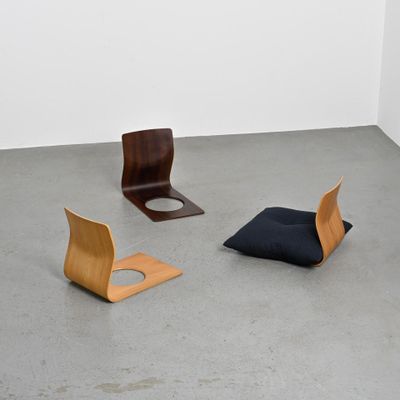 trois chaises et un coussin dans une pièce aux murs blancs