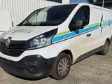 une camionnette blanche ornée d'une bande bleue et verte, garée devant un immeuble