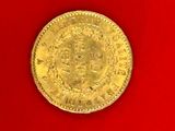 a close up of a gold coin on a red surface