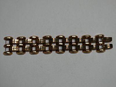 un gros plan d'un bracelet en or auquel est attachée une chaîne