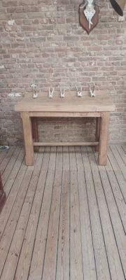 une table en bois au milieu d'une pièce dont l'un des murs est en briques