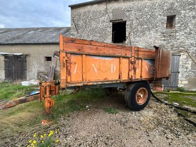 un camion-benne orange rouillé garé devant un immeuble