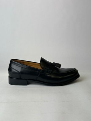 a pair of black loafers with tassels on them