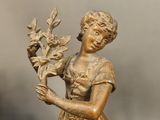 bronze statue of a woman holding a bouquet of flowers on a table