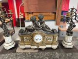 a clock sitting on top of a table surrounded by statues