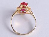 a close up of a gold ring with a red stone in it