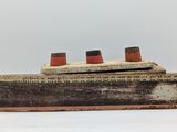 a small wooden model of a ship on a white surface