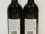 two bottles of red wine sitting on top of a white table