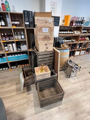 il y a de nombreuses caisses de vin par terre dans ce magasin