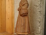 a wooden statue of a woman standing on a shelf