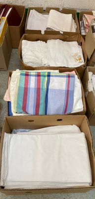 Plusieurs cartons de vêtements sont empilés par terre devant un mur.