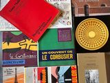 de nombreux livres posés sur un lit, avec une horloge en arrière-plan