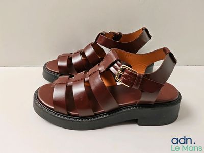 un gros plan sur une paire de sandales marron posées sur une surface blanche