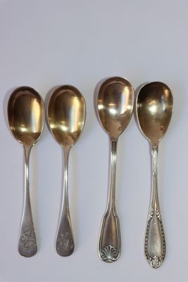 cinq cuillères en argent sont alignées sur une surface blanche