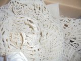 un gros plan sur un châle blanc au crochet, dans une boîte