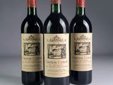 three bottles of red wine are lined up on a table
