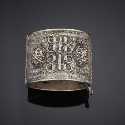 an antique silver bracelet with a cross and flowers on it