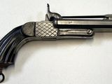 un vieux pistolet en forme de pistolet posé sur une surface blanche