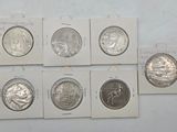 six different types of silver coins are on display on a white surface