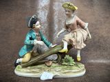 a figurine of a boy and a girl sitting on a log