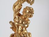 a gold statue of a man holding a bird on a branch