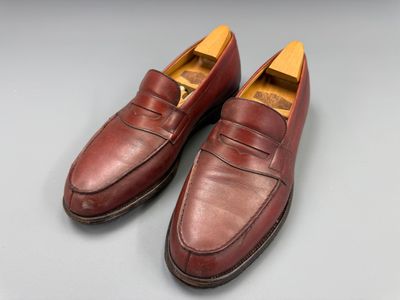 une paire de chaussures en cuir marron posées sur une surface grise