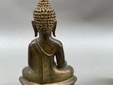 pair of antique bronze buddha statues on pedestals on a gray background