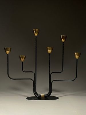 une image représentant un chandelier noir et doré à cinq bougies