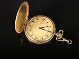 une montre de poche en or posée sur une surface noire