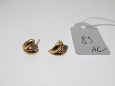 une paire de boucles d'oreilles en or et diamants posée sur une table blanche