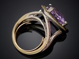 a close up of a ring with a purple stone on a black surface